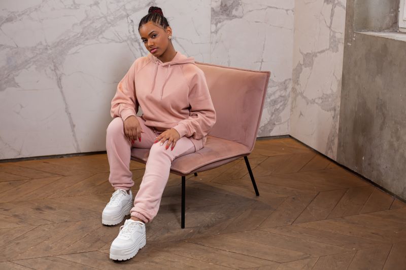 A girl on a chair wearing a pink tracksuit