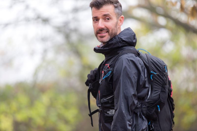 A man wearing a navy explorer jacket while in the woods