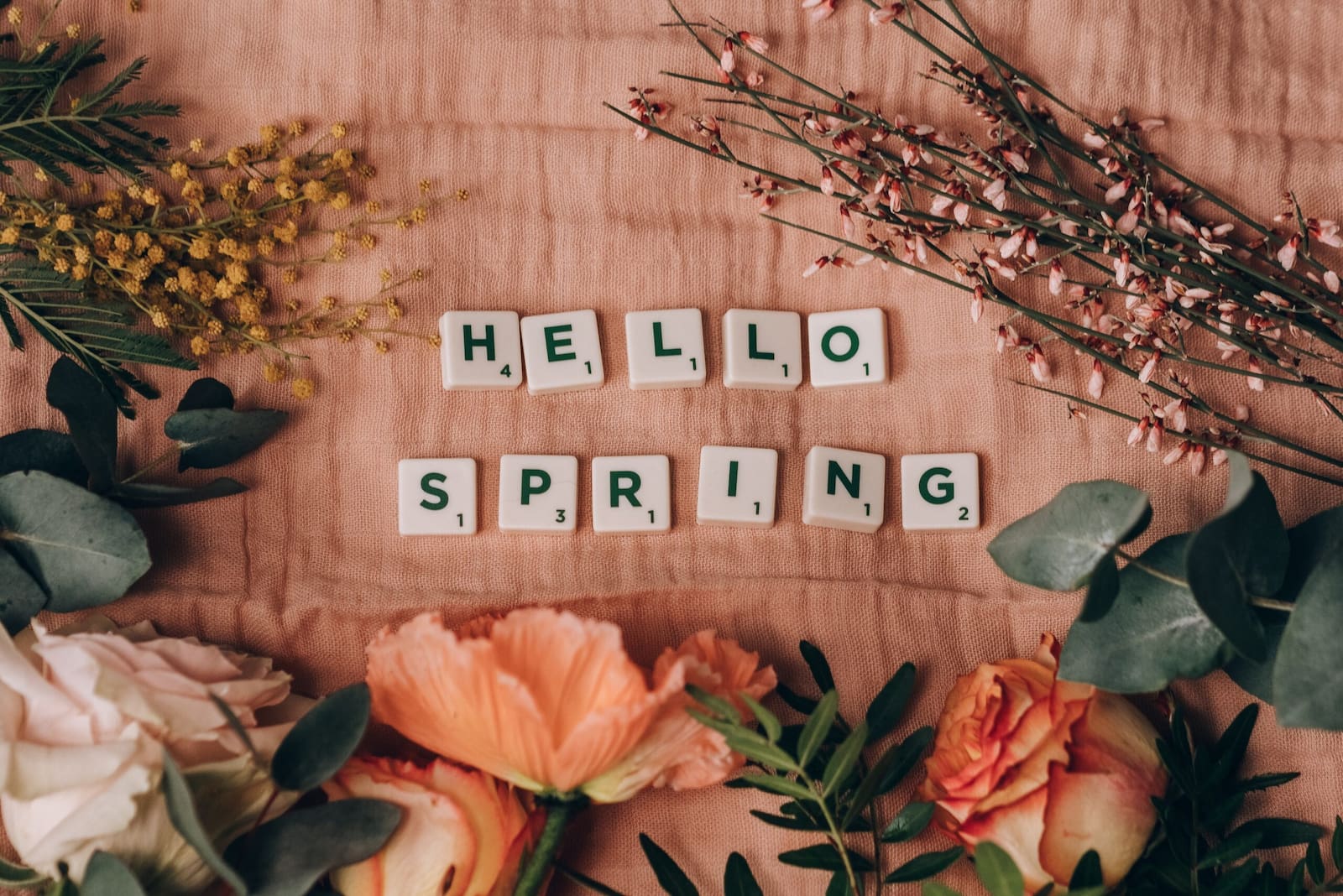 'hello spring' written with cubes surrounded by spring flowers