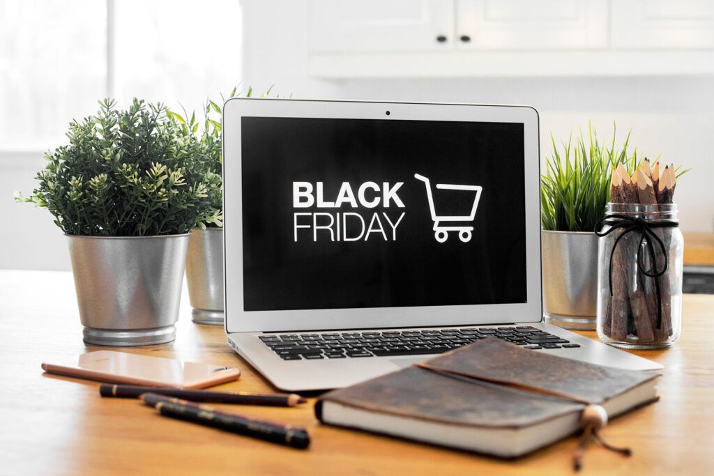 Black Friday is on a laptop screen, with a phone and notebook in the shot.