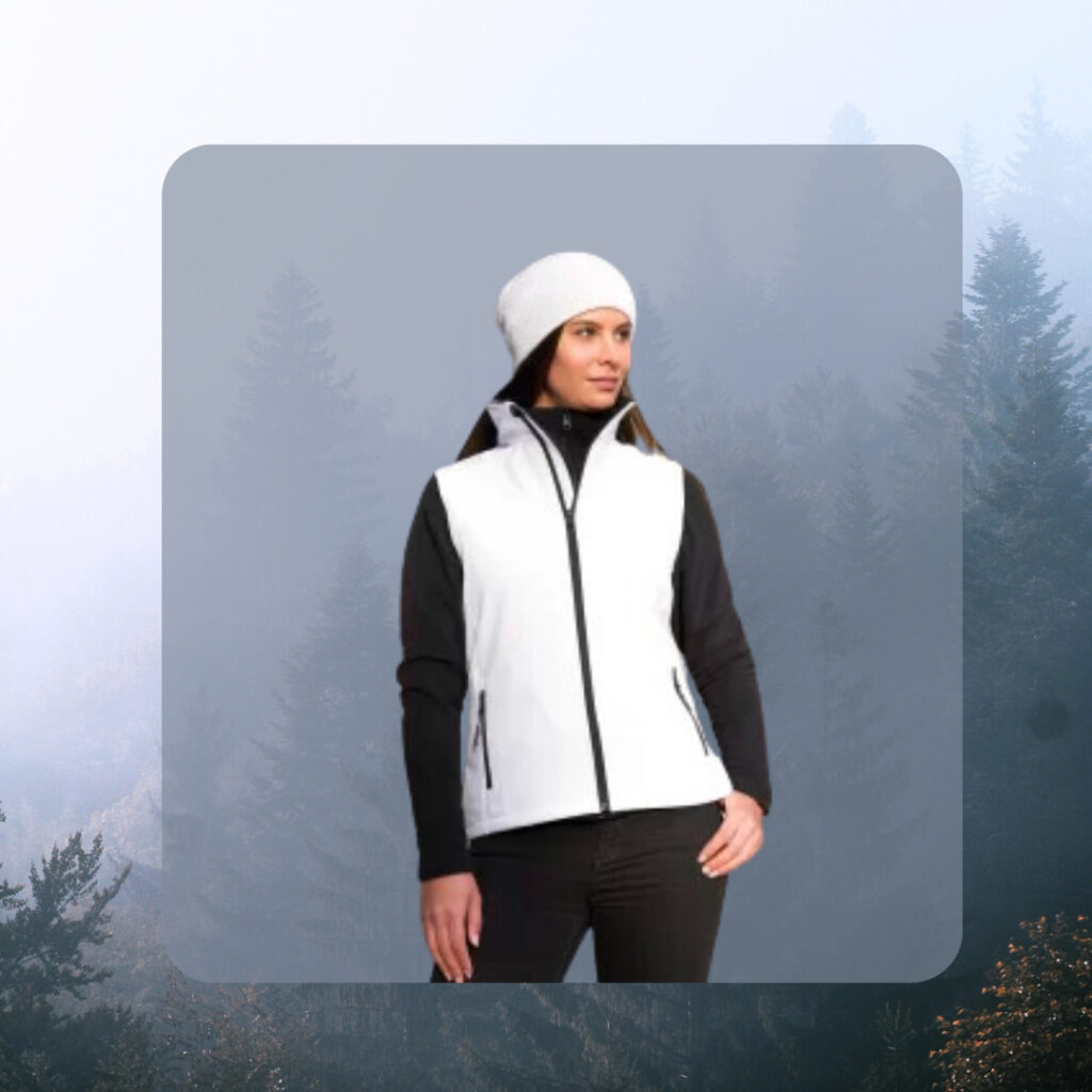 A woman is wearing a layered winter outfit. She's wearing a black long sleeve top, a white vest and a white beanie to top it off.