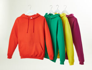Four different-coloured hoodies on hangers. The hoodies are orange, green, yellow and burgundy.