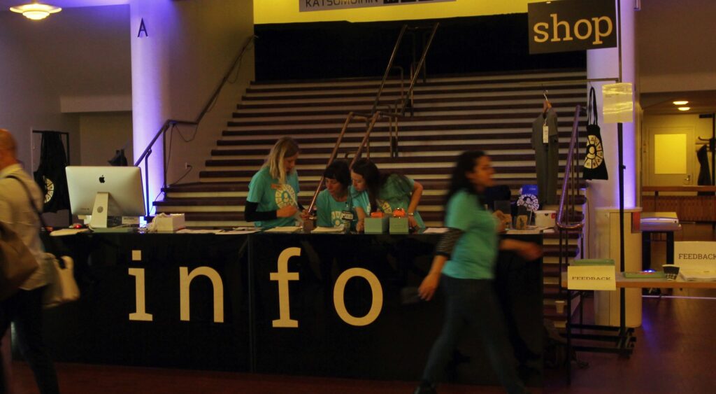 Workers at an information desk at a conference, with budget promo products