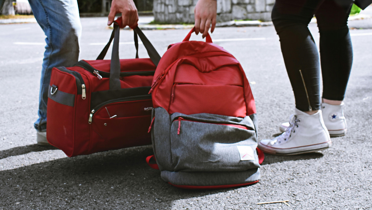Two people, one with a duffel bag, the other with a backpack